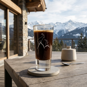 Verre à liqueur de montagne avec motif bouquetin, rempli de café, dans un décor de chalet contemporain.