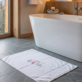 Tapis de bain montagne blanc brodé d'un motif télécabine rouge dans une salle de bain contemporaine.