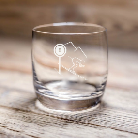 Bicchiere da acqua montagna Schuss con sciatore e cartello di pista, su un tavolo in legno