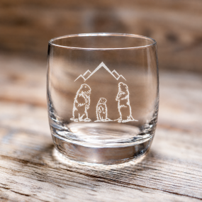 Bicchiere da acqua montagna con motivo di tre marmotte, su un tavolo in legno rustico