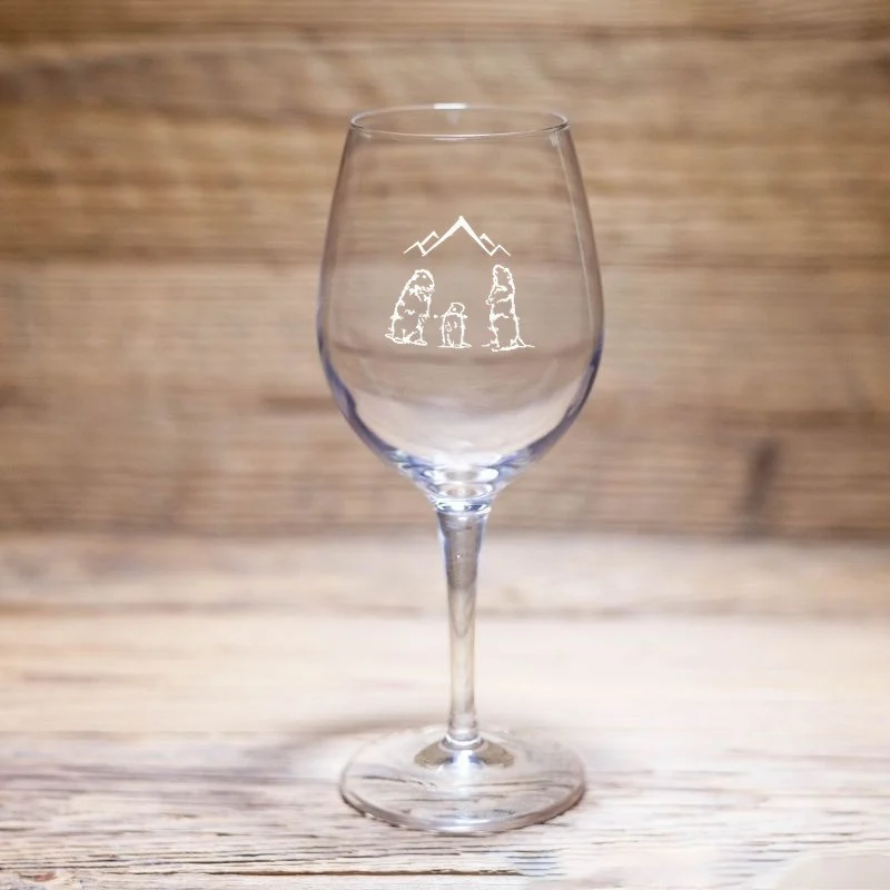Verre à vin montagne à motif trois marmottes et sommets, posé sur une table en bois.