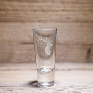 Vaso de chupito de montaña con ciervo, sobre una mesa de madera
